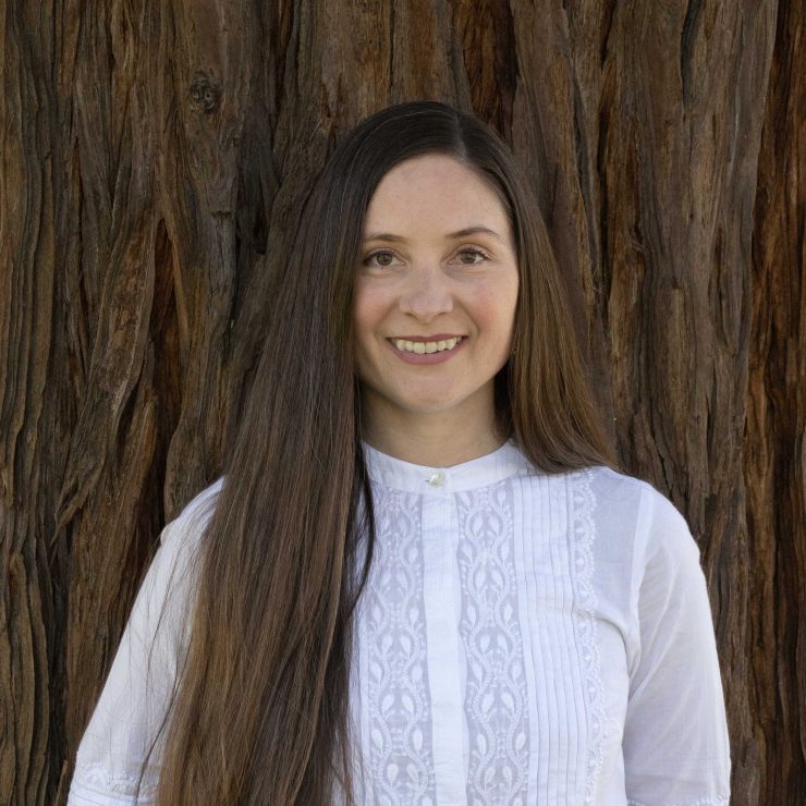 Professor Lauren Bausch smiling in front of a redwood tree